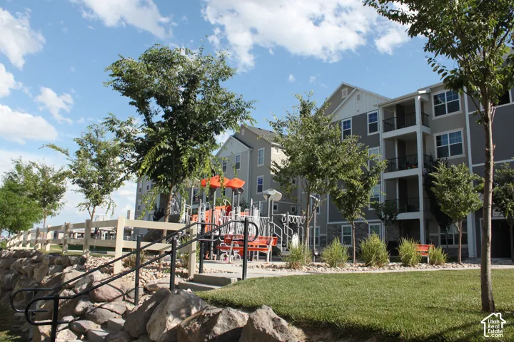 Expansive grounds featuring a manicured lawn, mature shade trees, and a multi-level playground structure with orange accents
