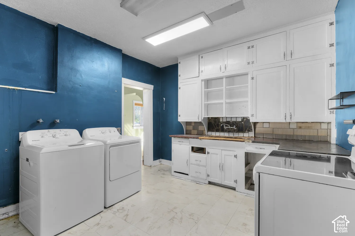 White cabinetry, tile backsplash, and light-toned flooring
