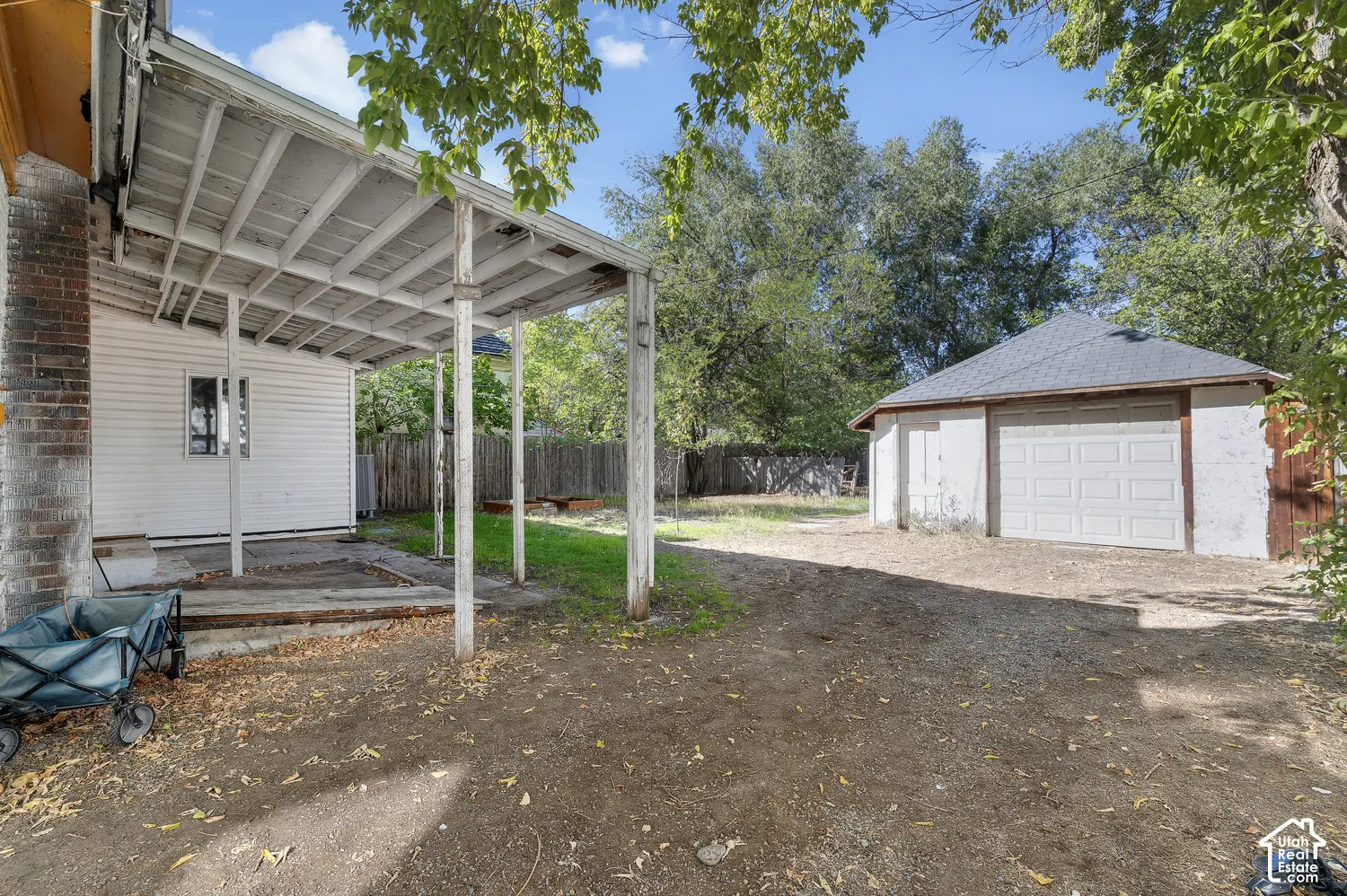 Detached garage with dual garage doors, covered patio with white wood supports, and a brick exterior wall
