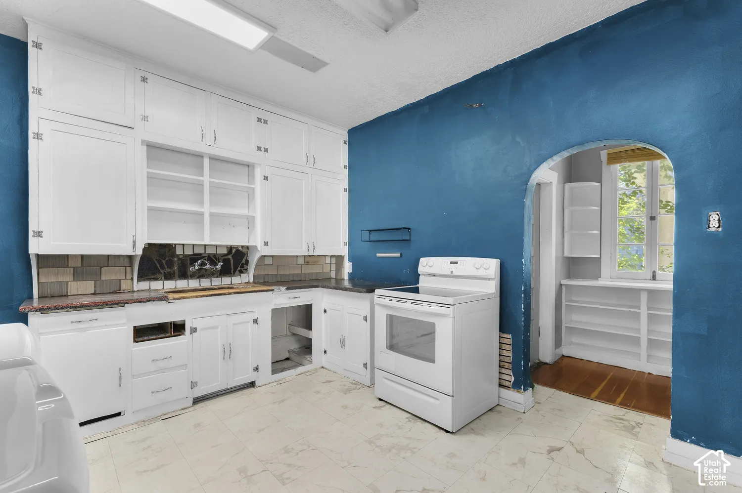 White cabinetry with open shelving, tile backsplash, and a built-in electric range