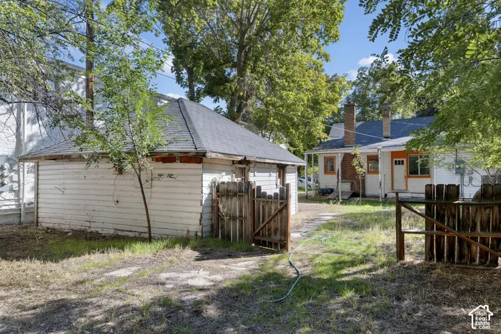 Detached garage structure with a shingled roof and wood siding