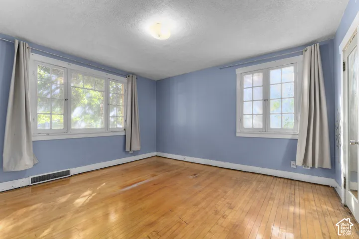Hardwood flooring, multiple windows, overhead flush-mount lighting, and light blue wall finish