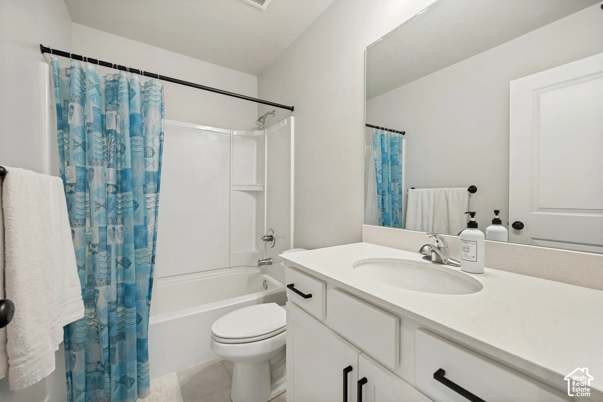 White vanity with integrated sink, chrome faucet, and expansive mirror