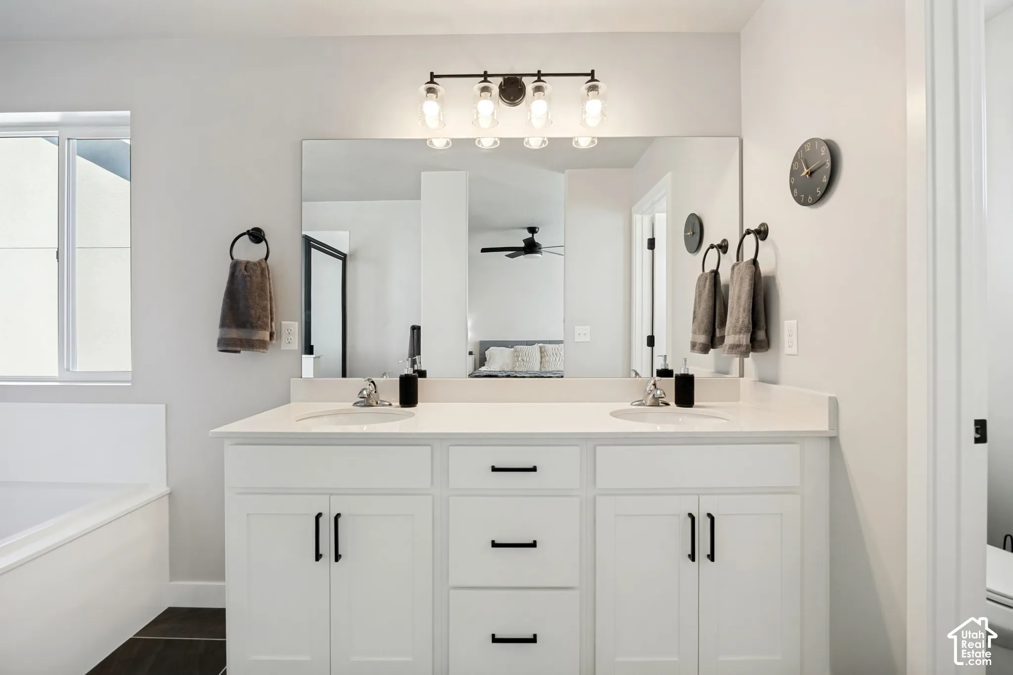 Dual vanity with white cabinetry, matte black hardware, and light-toned countertops