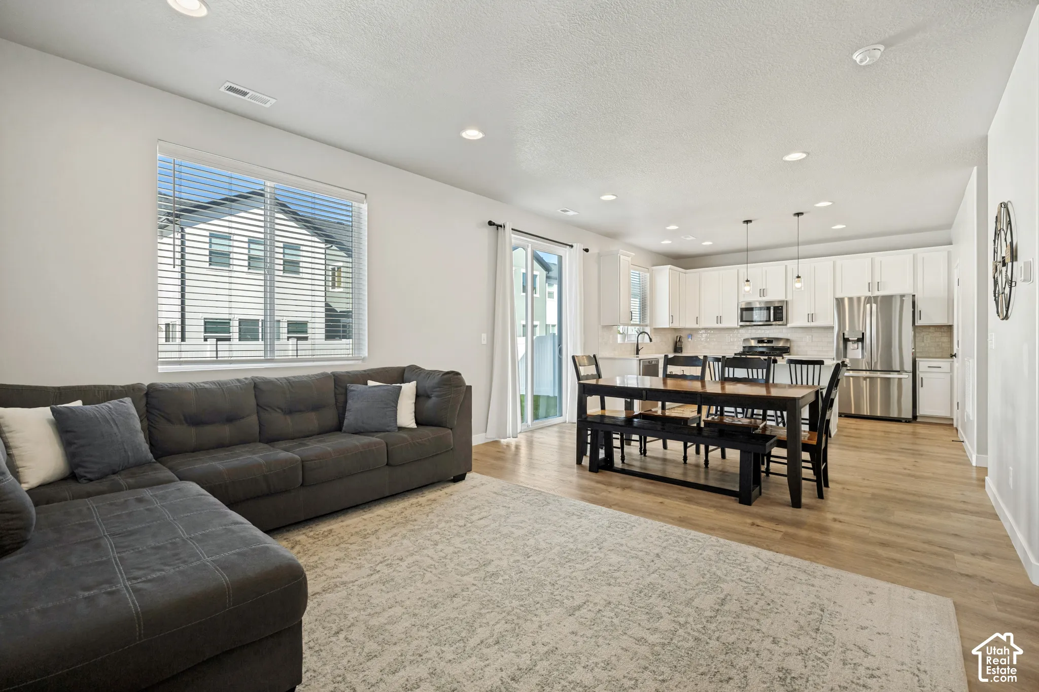 Open-concept living space featuring wood-finish flooring, recessed lighting, and a sliding glass door