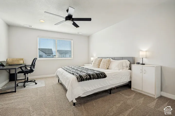 Bright room featuring a window with horizontal blinds, a ceiling fan with integrated lighting, and neutral carpet flooring