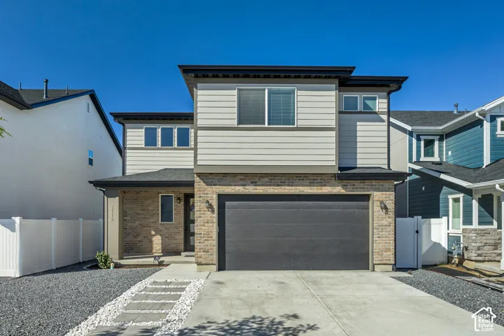 Contemporary exterior featuring a brick and siding facade, an integrated garage, a concrete driveway, and a stone walkway