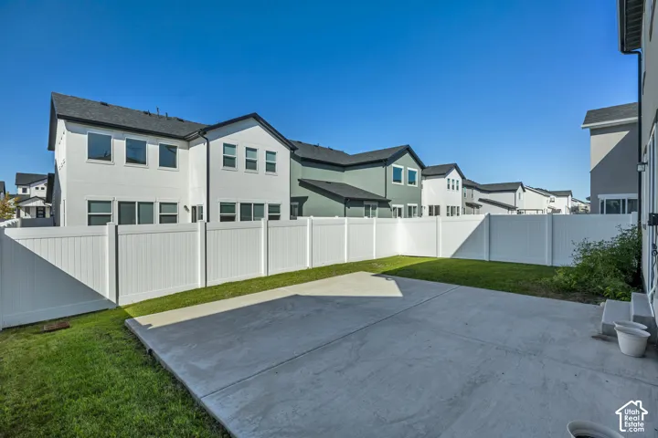 Expansive concrete patio with a surrounding white privacy fence, featuring a grassy area