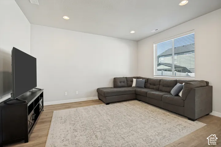 Recessed ceiling lighting, light wood-finish flooring, and a large window with blinds