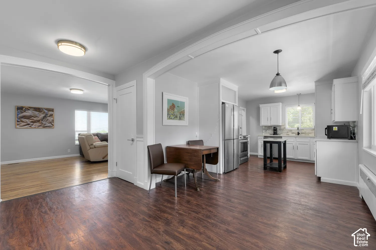 Spacious interior featuring wood-finish flooring, white cabinetry, stainless steel appliances, and a tile backsplash