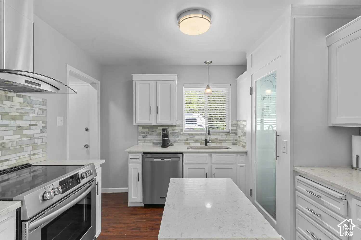 Kitchen featuring white cabinetry, light-toned countertops, stainless steel appliances, and a tiled backsplash