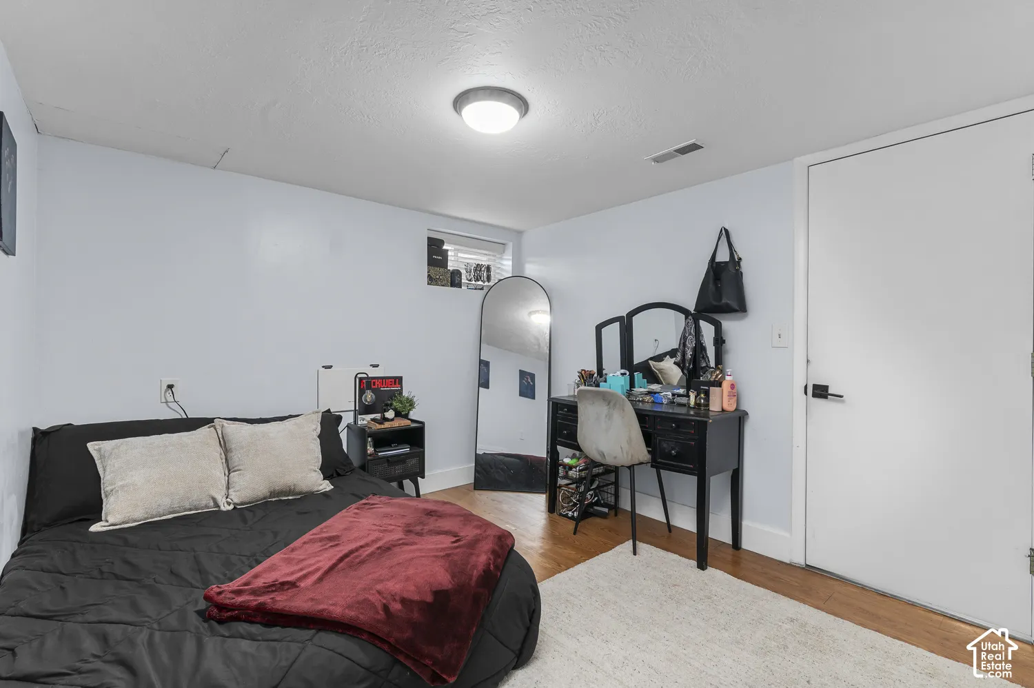 Hardwood-finish flooring, light blue wall paint, white trim, and a white interior door with black hardware