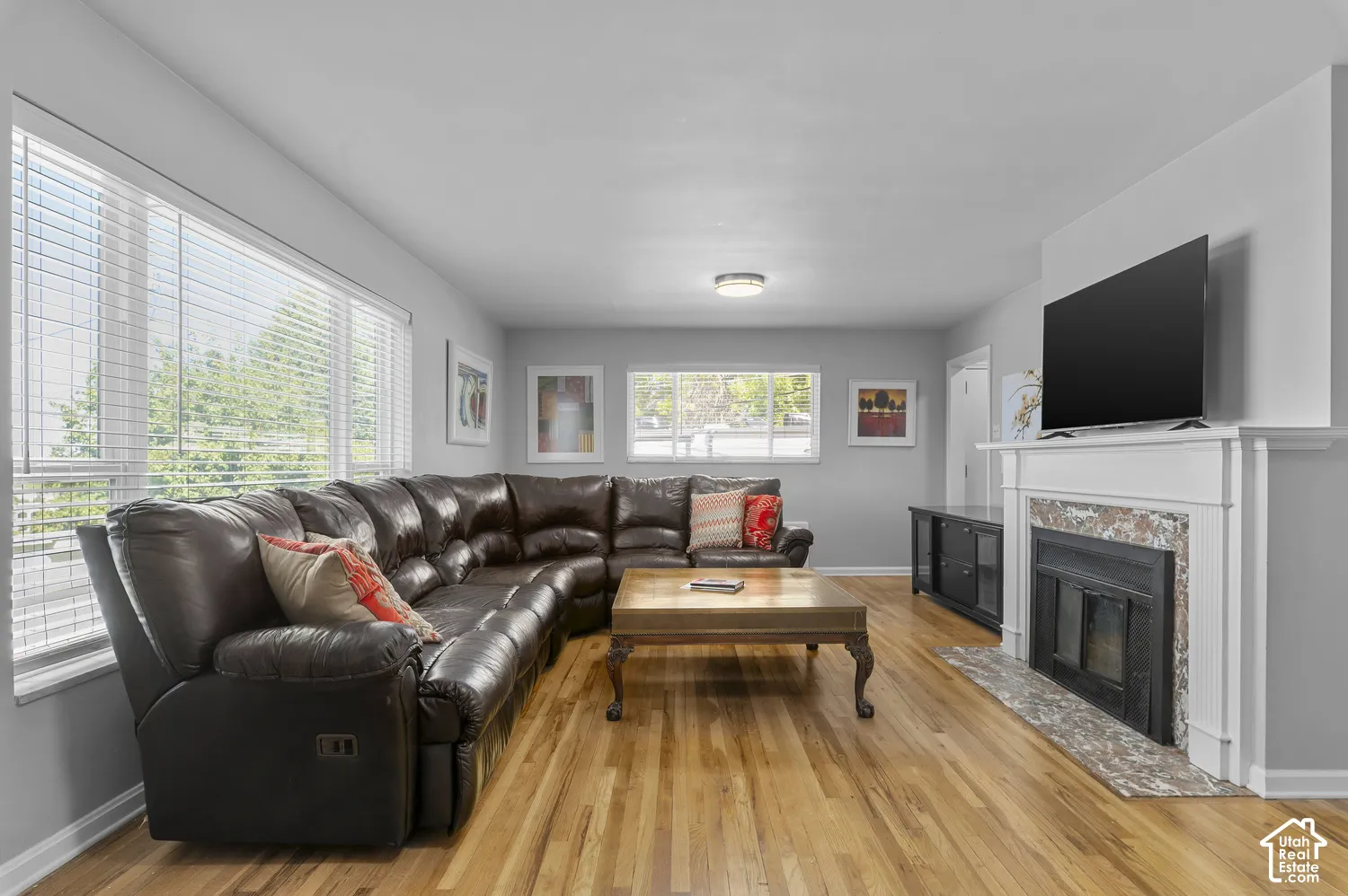 Hardwood flooring, multiple windows with blinds, built-in fireplace with mantel, and flush-mount lighting fixtures