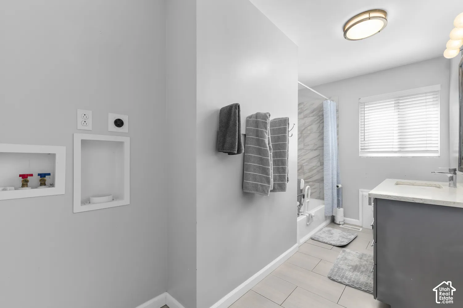 Integrated laundry hookups, tiled flooring, white window blinds, full bathroom with bathtub, and single vanity with a white countertop