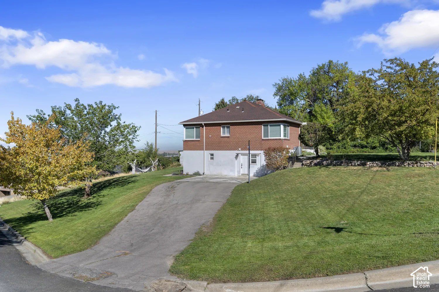 Brick facade residence with a pitched roof, featuring a sloped driveway and an attached garage