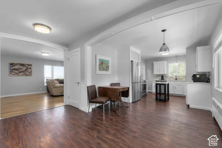 Spacious interior featuring wood-finish flooring, white cabinetry, stainless steel appliances, and a tile backsplash