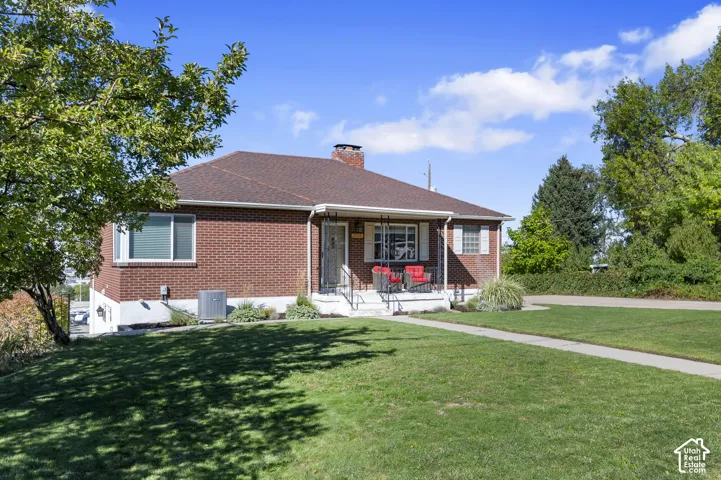 Brick exterior with a brown shingle roof, a covered front porch, and a concrete walkway