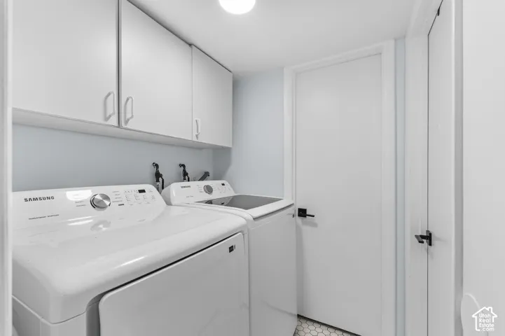 White upper cabinetry, light blue wall paint, white doors with black hardware, and hexagonal floor tiling