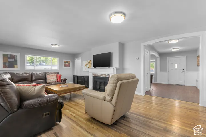 Hardwood flooring, fireplace with white mantel, archway entry, recessed lighting, and white paneled walls