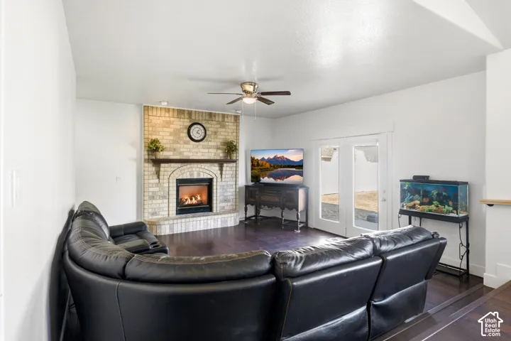 Brick-faced fireplace with a wood mantel, dark wood-finish flooring, recessed lighting, and a ceiling fan