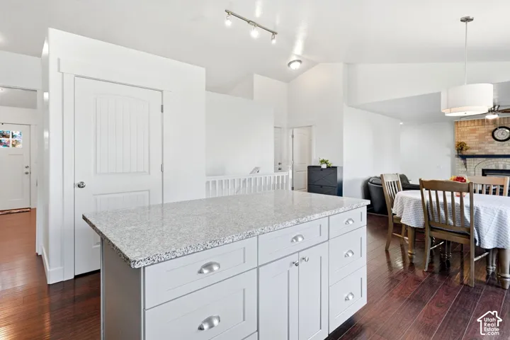 Kitchen island with light-toned countertop, white cabinetry with silver hardware, and wood-finish flooring