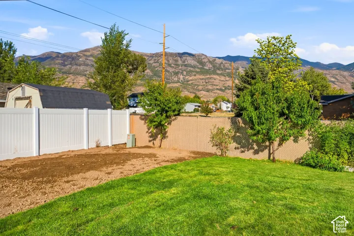 Expansive backyard area featuring a partial manicured lawn, a level soil pad, and a white privacy fence