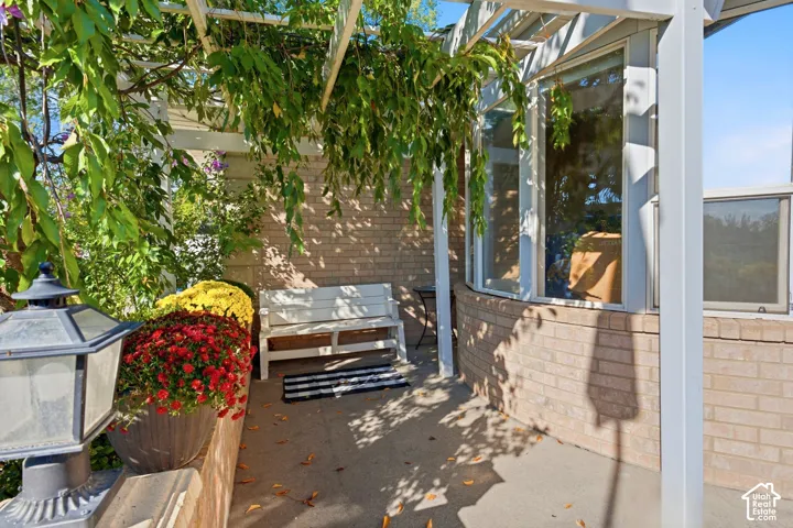 Exterior featuring a brick facade, bay window, and a pergola with established foliage