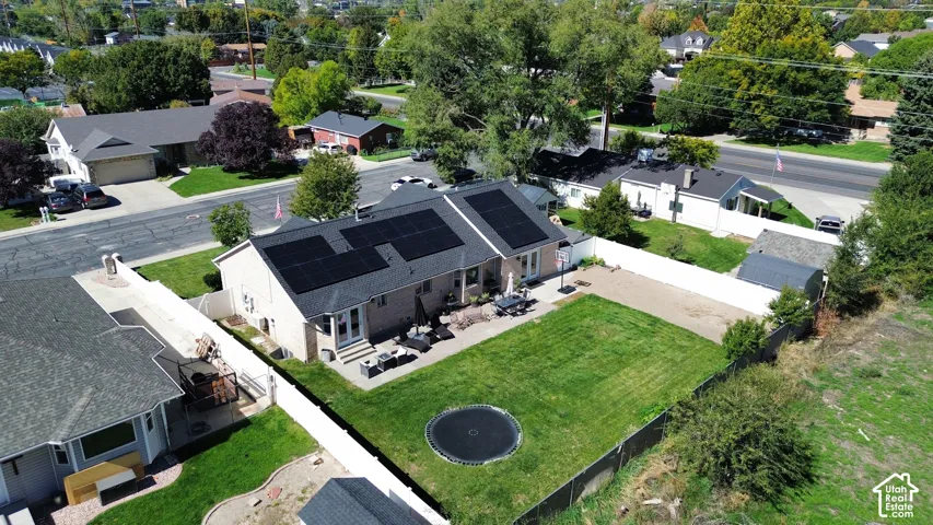 Rear exterior featuring solar panels, a manicured lawn, and a paved patio