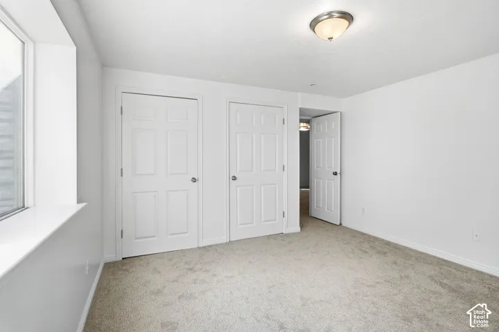 Carpeted room with a window, two paneled doors, a flush-mount ceiling light fixture, and an open doorway