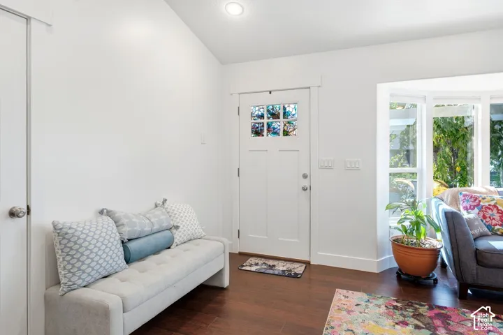 Wood-finish flooring with a white trim, featuring a white door with a stained-glass pane, recessed lighting, and a bay window