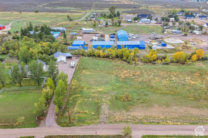 Expansive property featuring a gravel driveway, multiple structures including a main residence and outbuildings, and extensive open land