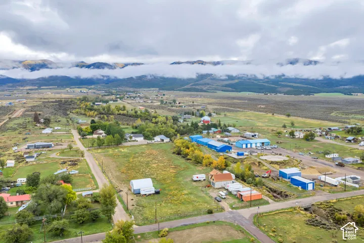 Aerial perspective of a rural community with multiple structures, expansive natural terrain, and distant mountains
