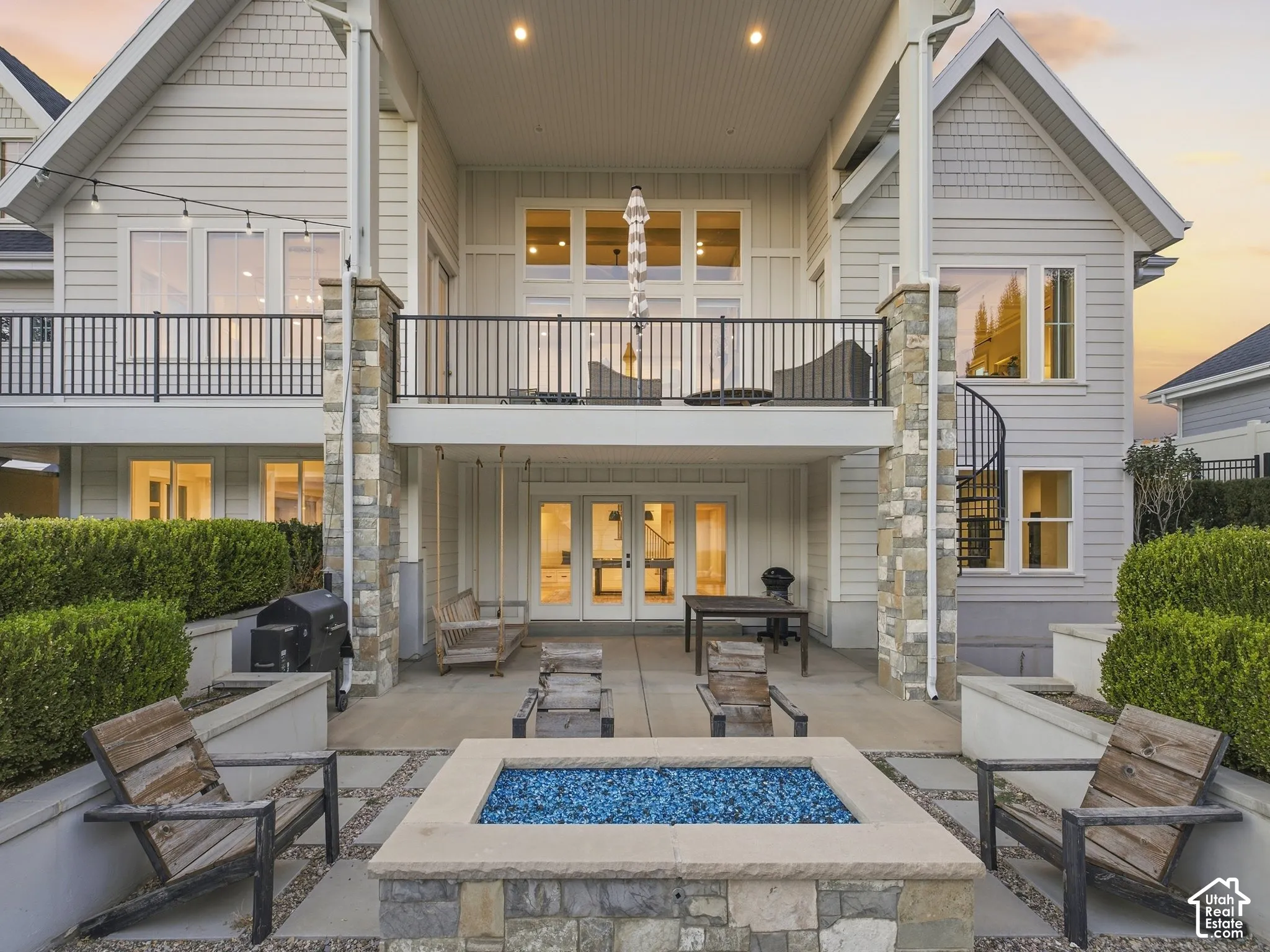 Multi-level outdoor living space featuring a ground-level patio, fire pit, and an upper-level balcony with a black metal railing