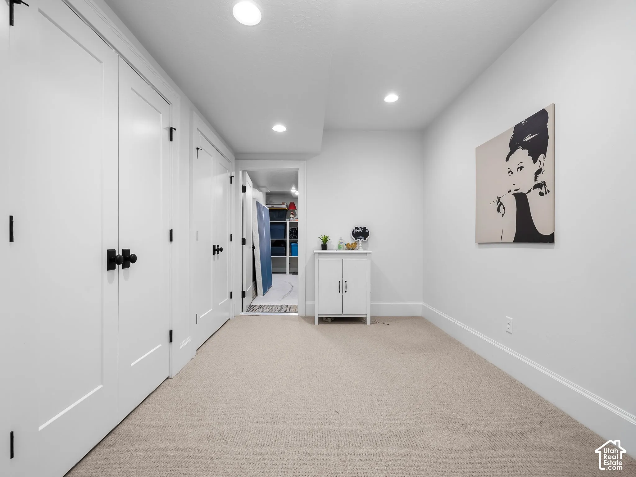 Recessed lighting illuminating the carpeted flooring and white walls