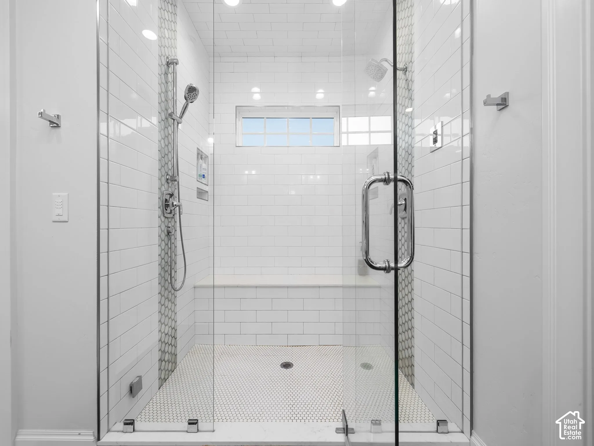 Glass-enclosed shower with subway tile walls, hexagon tile flooring, built-in bench, and multiple shower heads
