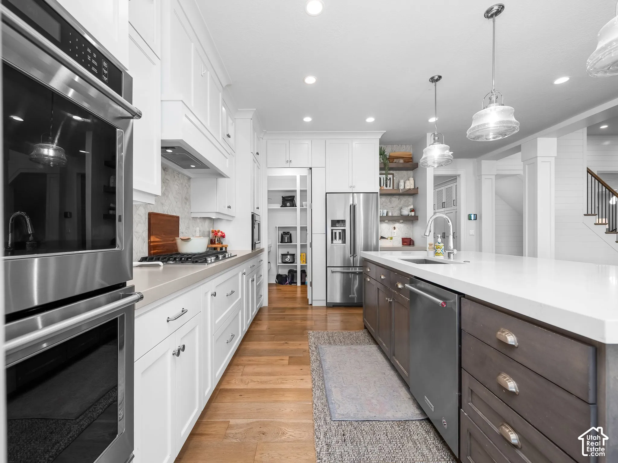 Bright kitchen featuring stainless steel appliances, white cabinetry, a large kitchen island, wood-finish flooring, and recessed lighting