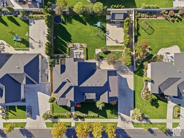 Expansive property featuring a dark-toned roof, substantial front yard landscaping, concrete driveway, and a spacious backyard with a patio