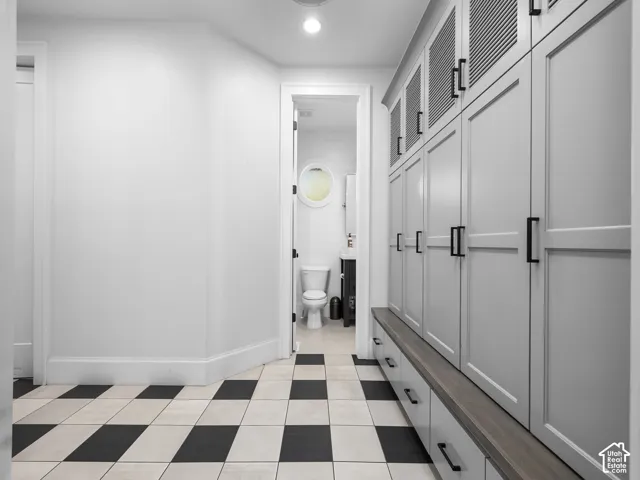Built-in storage cabinetry with matte black hardware, wood-finish bench, and black and white checkered floor tiles