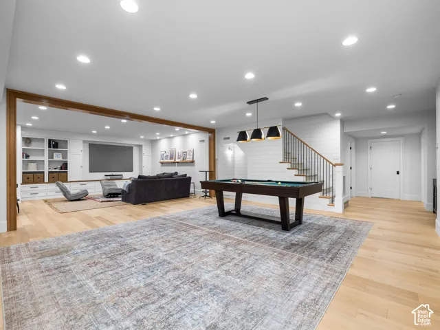 Spacious open-concept living area featuring light wood-finish flooring, recessed lighting, and a custom built-in entertainment center