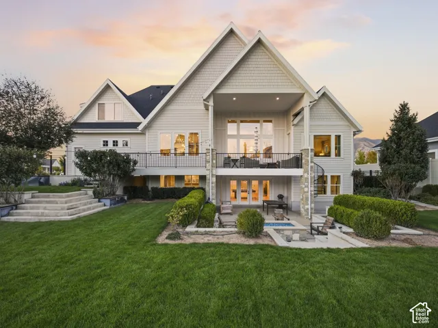Expansive green lawn, multi-level concrete steps, raised planter beds, ground-level patio, and an upper-level balcony with a spiral staircase