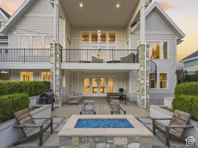 Multi-level outdoor living space featuring a ground-level patio, fire pit, and an upper-level balcony with a black metal railing