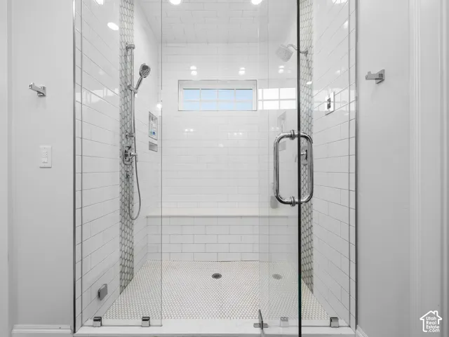 Glass-enclosed shower with subway tile walls, hexagon tile flooring, built-in bench, and multiple shower heads