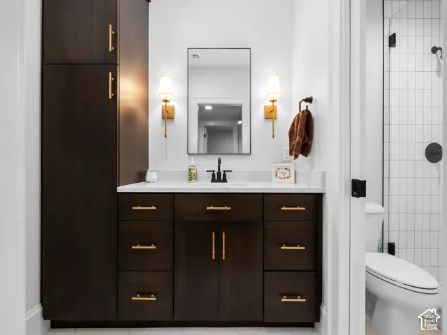 Dark wood-finish cabinetry, white countertop, rectangular vanity mirror, and dual sconce lighting