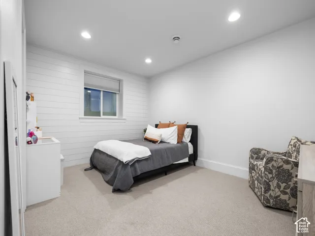 Recessed lighting, window with roller shade, shiplap accent wall, carpet flooring