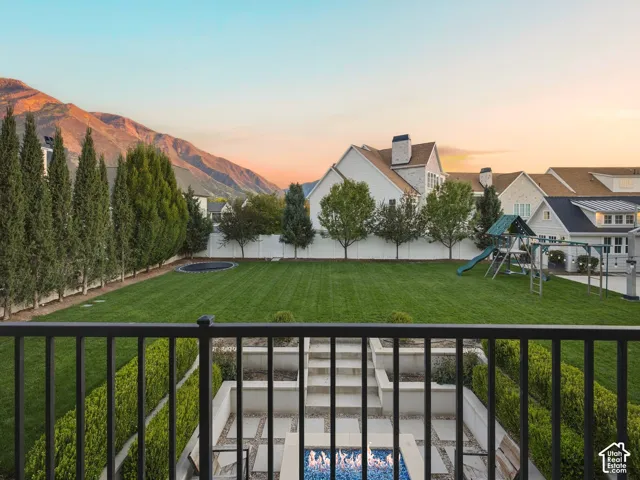 Expansive backyard featuring a manicured lawn, tiered landscaping, a fire pit, and privacy plantings along the perimeter