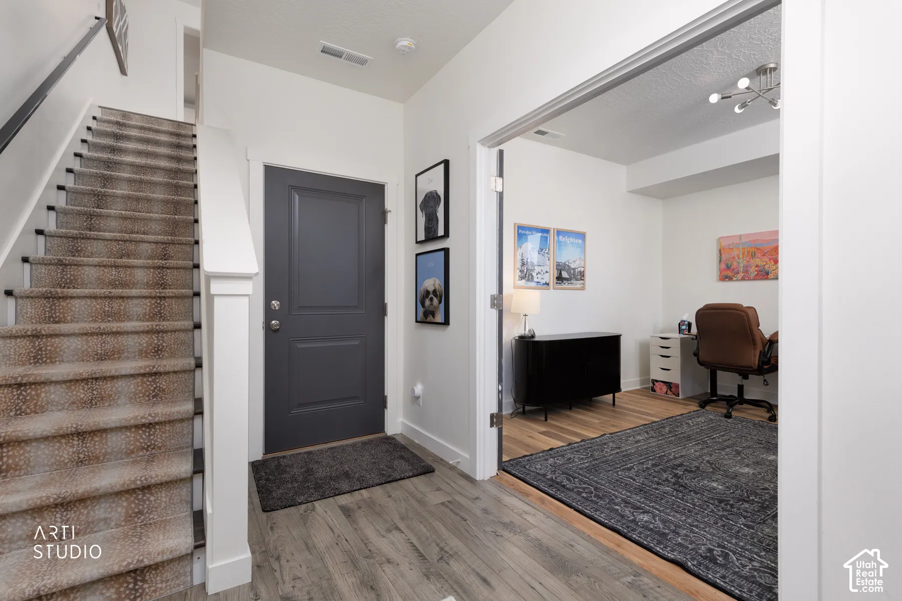 Wood-finish flooring, staircase with patterned carpet, and a dedicated room with a modern light fixture