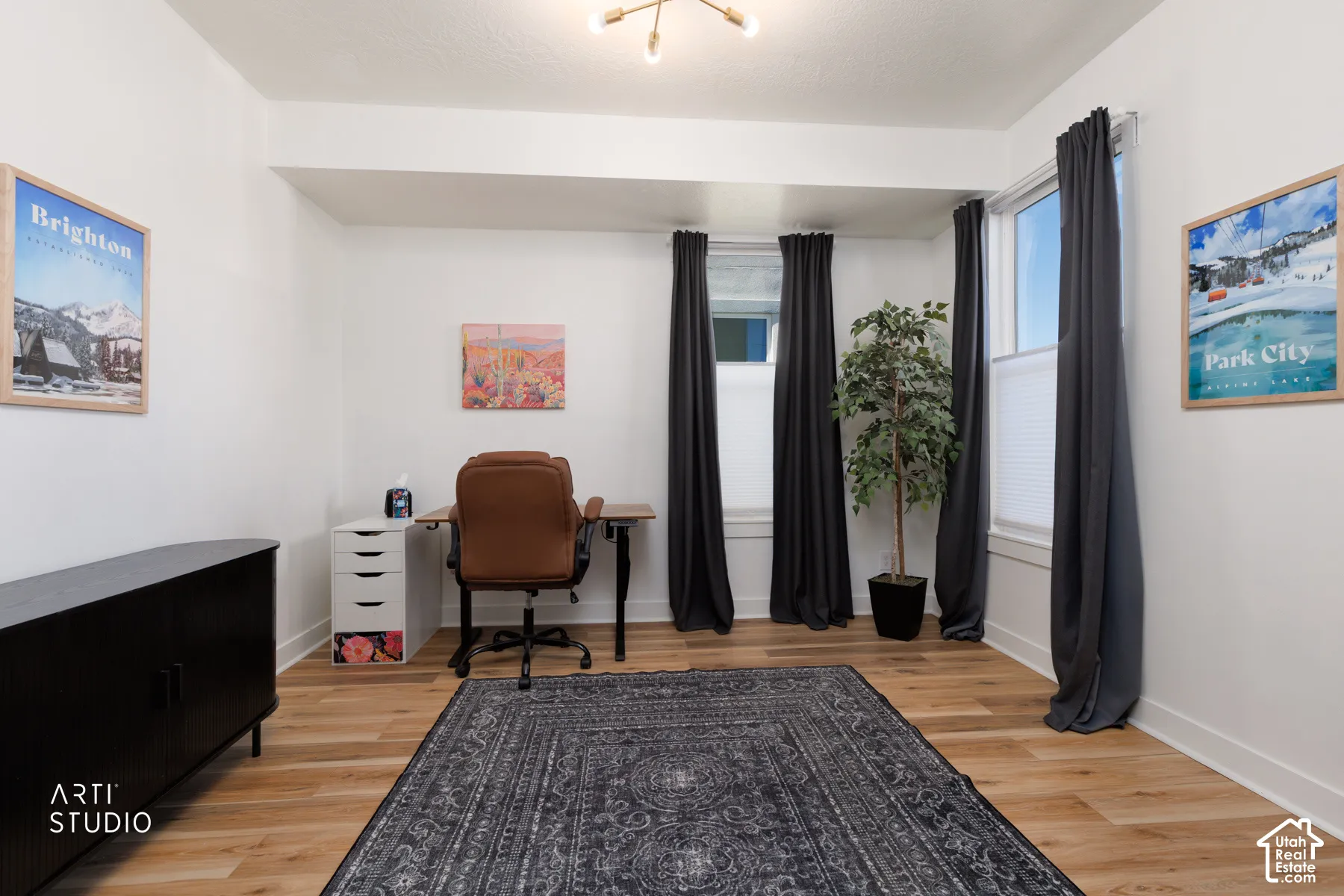 Wood-finish flooring, white walls, multiple windows with blinds, and an overhead light fixture