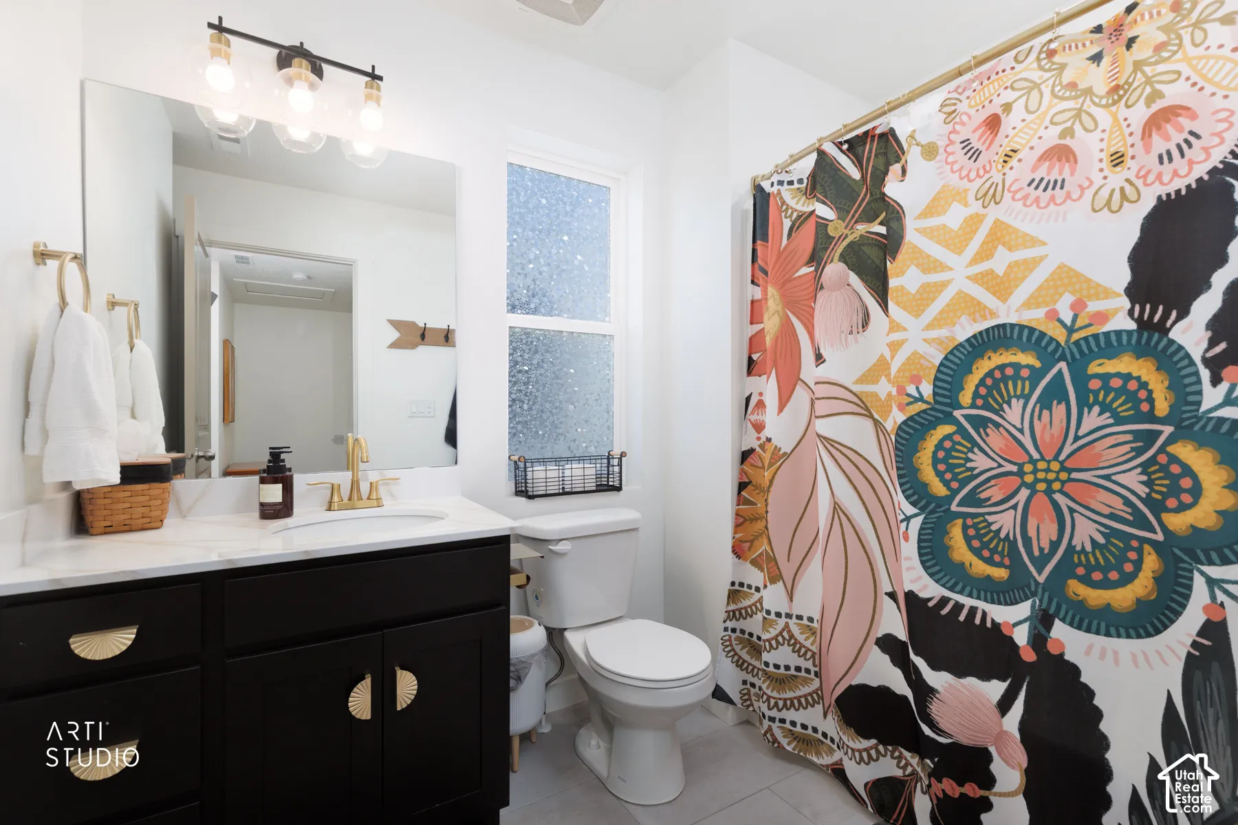 Black vanity with gold-toned hardware, white countertop, and integrated sink
