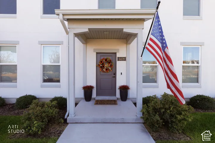 Stucco exterior with contrasting trim, covered entry porch, and mature landscaping