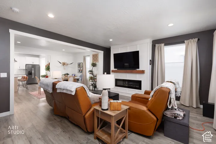 Wood-finish flooring, recessed lighting, and a built-in fireplace with a wood mantle